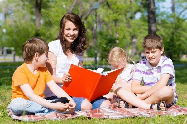 teacher reads a book to children in a summer park Stock photo © adam121