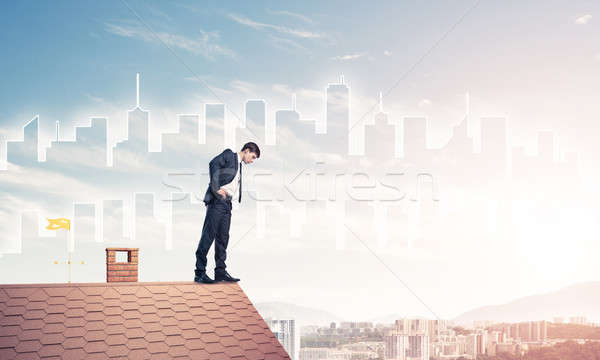 Businessman looking down from roof and modern cityscape at backg Stock photo © adam121