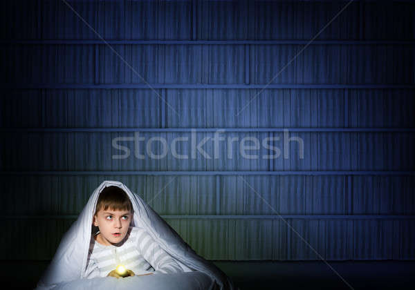 Stock photo: boy under the covers with a flashlight