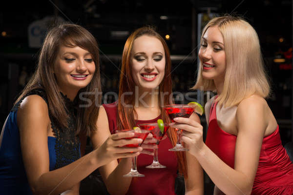 Stock photo: three girls raised their glasses in a nightclub