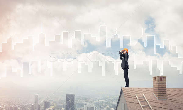Engineer man standing on roof and looking in binoculars. Mixed m Stock photo © adam121