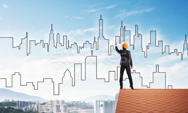 Man architect draw silhouette of modern city on blue sky. Mixed media Stock photo © adam121