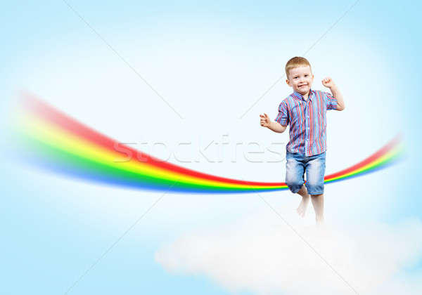 Stock photo: boy jumping on clouds and a rainbow