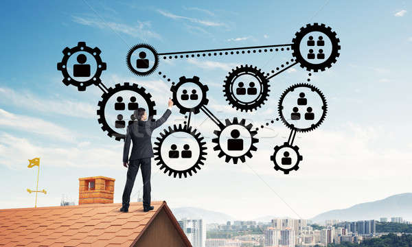 Businessman on house roof presenting teamwork and connection con Stock photo © adam121