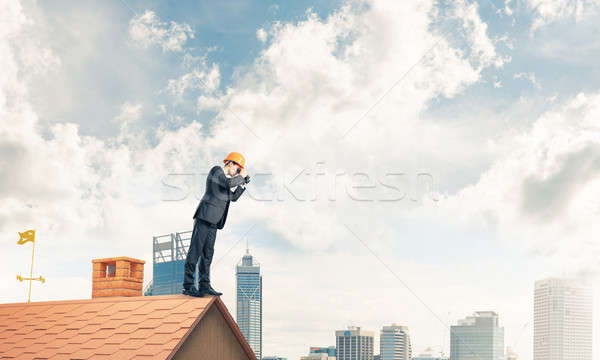 Engineer man standing on roof and looking in binoculars. Mixed m Stock photo © adam121