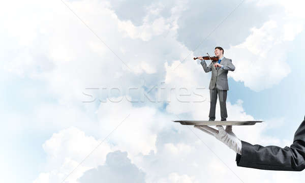 Businessman on metal tray playing violin against blue sky background Stock photo © adam121