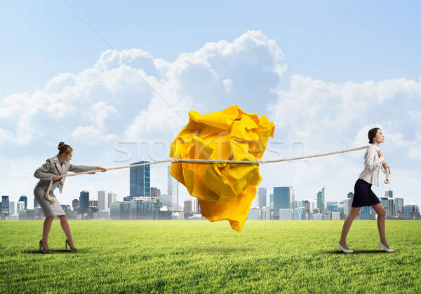 Stock photo: Two women pulling with effort big crumpled ball of paper as creativity sign