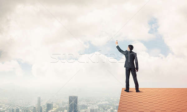 Businessman on house roof touch empty space. Mixed media Stock photo © adam121