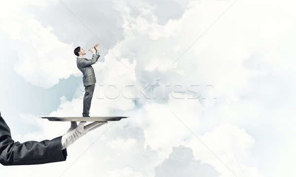 Businessman on metal tray playing fife against blue sky backgrou Stock photo © adam121