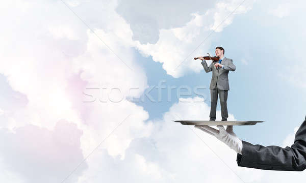 Businessman on metal tray playing violin against blue sky background Stock photo © adam121