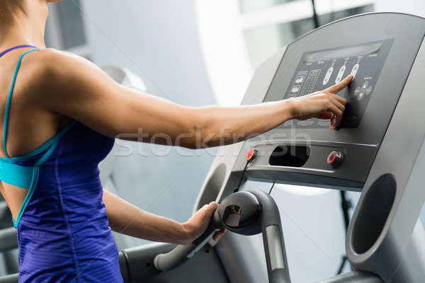 Stock photo: woman adjusts the treadmill