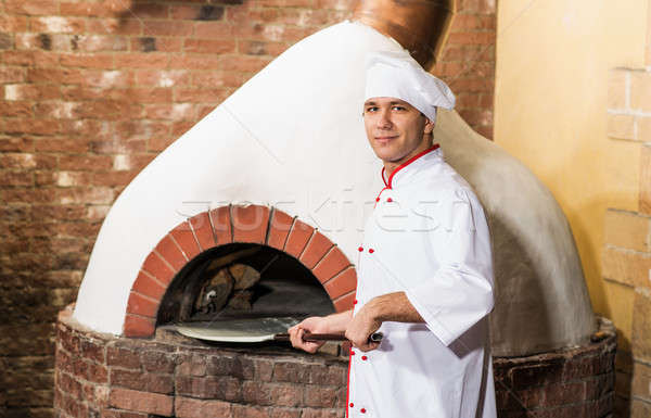 Chef puts dough in the oven for pizzas, Stock photo © adam121