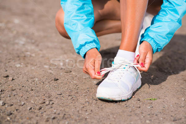 Stock photo: young woman tying shoelaces on sneakers