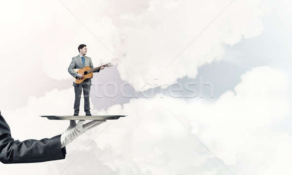 Businessman on metal tray playing acoustic guitar against blue s Stock photo © adam121