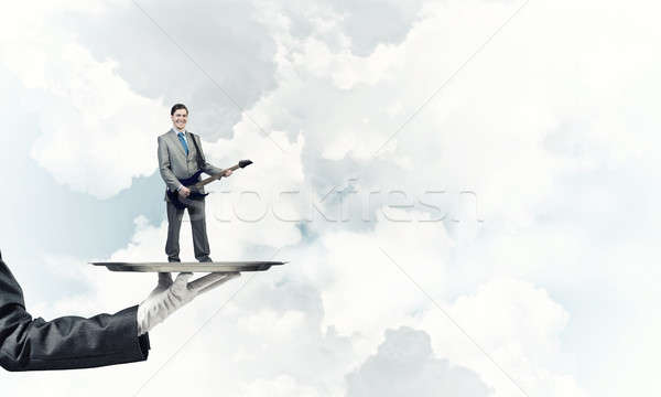 Businessman on metal tray playing electric guitar against blue sky background Stock photo © adam121