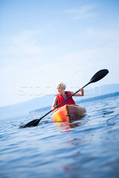 Stock photo: Woman With Safety Vest Kayaking Alone on a Calm Sea