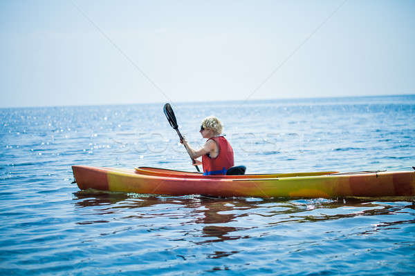 Stock photo: Woman With Safety Vest Kayaking Alone on a Calm Sea