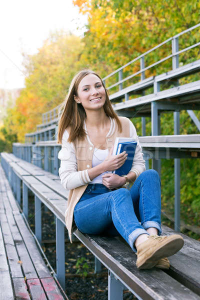 Student sitting on sport tribune with book and smiling Stock photo © Agatalina