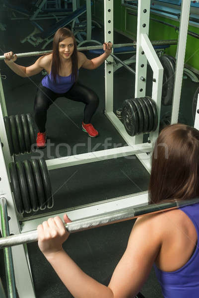 Stock photo: Woman doing shoulder exercise with weight bar