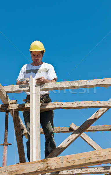 Construction worker on scaffold busy on formwork preparation Stock photo © akarelias