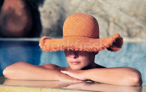 Attractive young woman in hat resting by the side of a pool Stock photo © akarelias