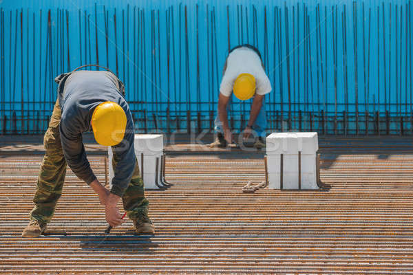 Construction workers installing binding wires to steel bars Stock photo © akarelias