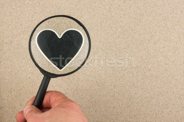 Hand with magnifying glass over the heart in the sand Stock photo © alekleks