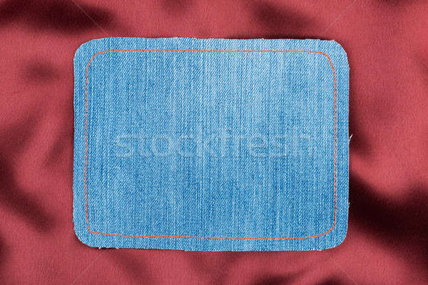 Frame made of denim fabric with yellow stitching on red silk Stock photo © alekleks