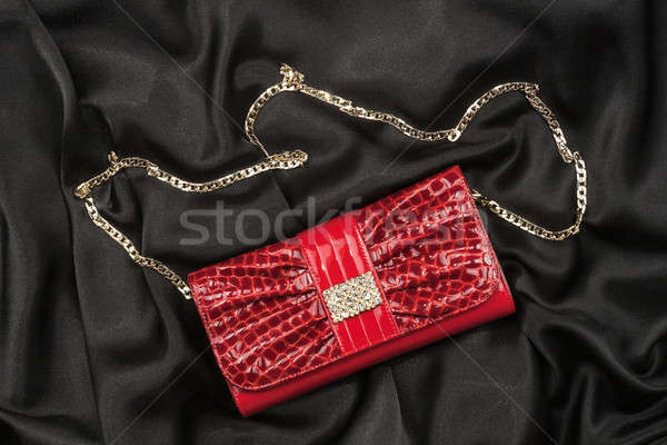 Red lacquer bag lying on a black silk Stock photo © alekleks