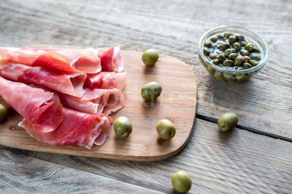 Jamon with capers and olives on the wooden board Stock photo © Alex9500