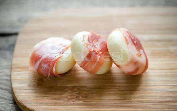 Stock photo: Mini cheese and prosciutto wraps on the wooden board