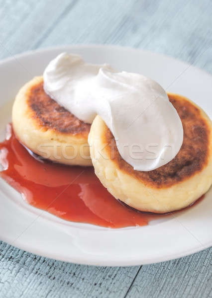 Stock photo: Cottage cheese patties with whipped cream and berry syrup