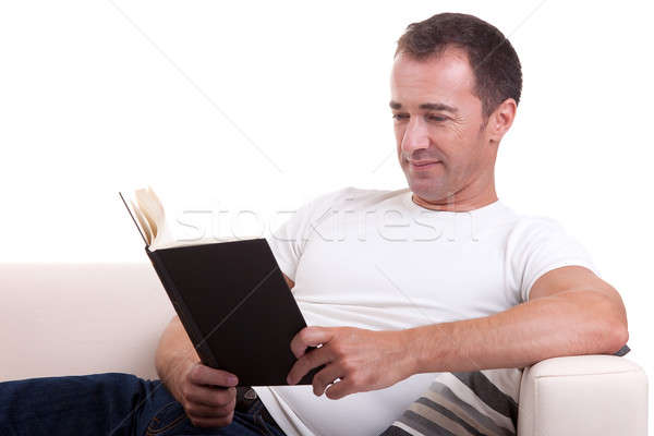 middle-age man lying on the sofa reading a book, isolated on white background, studio shot. Stock photo © alexandrenunes
