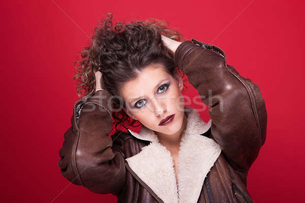 young and beautiful woman, with curly hair, holding her hair with a winter coat, on red background,  Stock photo © alexandrenunes