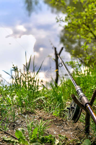 Fishing rod on the river bank among greenery on a fishing trip in the spring. Stock photo © AlisLuch