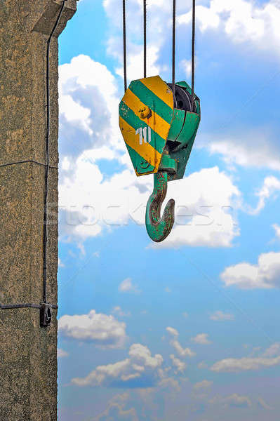 Yellow-green hook of a construction crane on a rope on a background of clouds Stock photo © AlisLuch