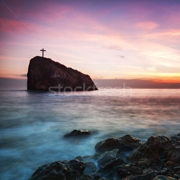 Stock photo:  Seacoast at sunset and a cross on a rock