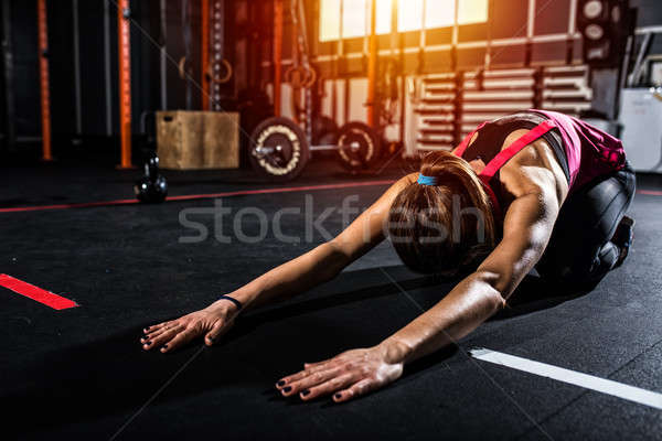 Stock photo: Athletic girl does stretching exercises at the gym