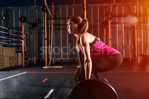 Athletic girl works out at the gym with a barbell Stock photo © alphaspirit