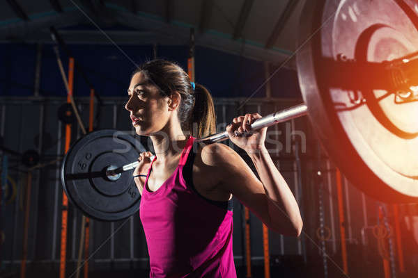 Stock photo: Athletic girl works out at the gym with a barbell