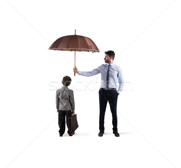 Stock photo: Businessman with umbrella that protect a child. Concept of young economy and startup protection