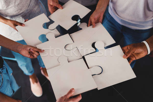 Team of young businessmen combine pieces of puzzle. Concept of integration and partnership Stock photo © alphaspirit