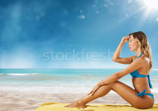 Girl in bikini sits on a beach looking for new travel destination. Stock photo © alphaspirit