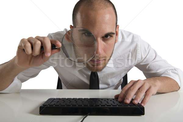 Businessman looks on the computer with a  lens Stock photo © alphaspirit