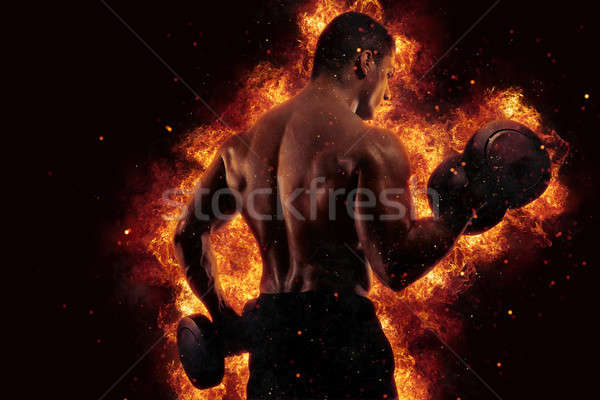 Athletic man training biceps at the gym with fire effect Stock photo © alphaspirit