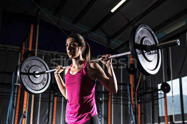 Athletic girl works out at the gym with a barbell Stock photo © alphaspirit