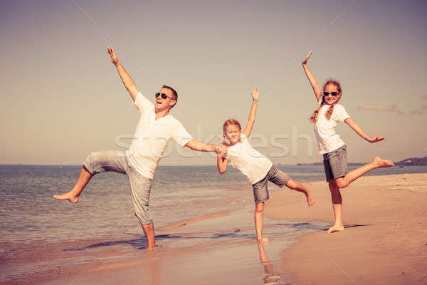 Father and daughters playing on the beach at the day time. Stock photo © altanaka