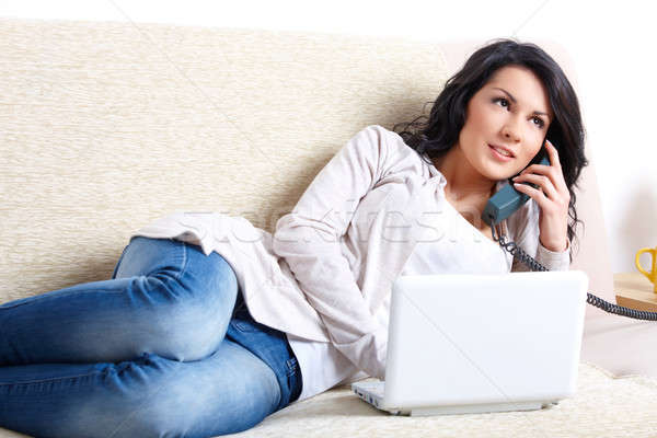 Beautiful woman with netbook and phone laying on sofa Stock photo © Amaviael