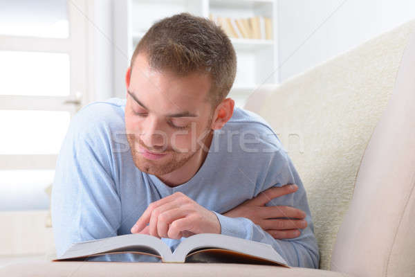 Fiatalember olvas könyv mosolyog jóképű kanapé Stock fotó © Amaviael