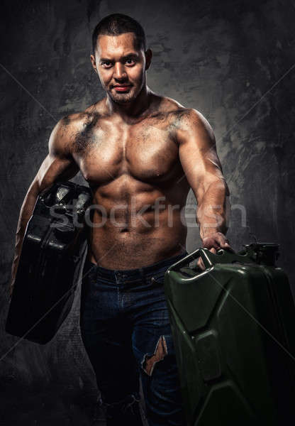 Stock photo: Muscular man with two metal fuel cans indoors